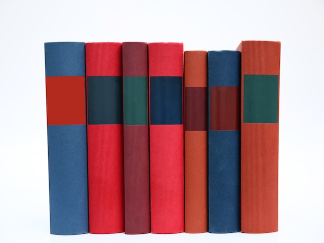 Seven book spines stand together in a row. Photo by Pixabay